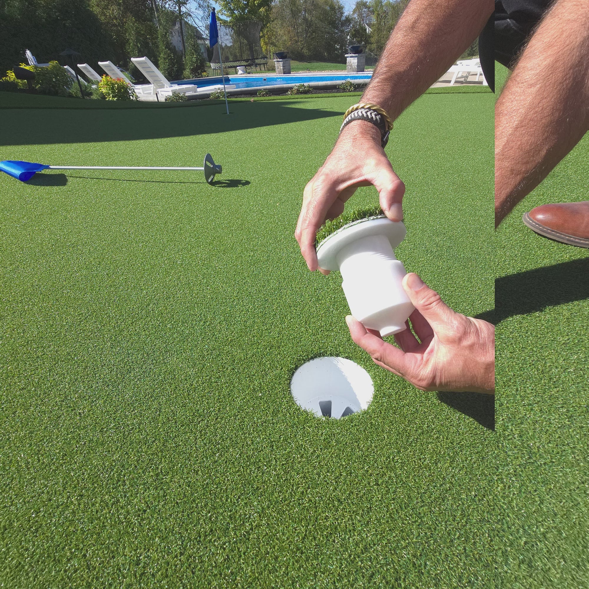 Before and after picture of a man holding a golf cup insert in his hands over top of a putting green golf hole, then in the 2nd picture it shows the golf cup insert in the golf hole and the green turf on top of it is flush with the putting green turf. 